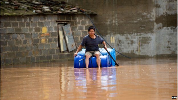 This picture taken on 21 July 2014 shows a man making his way through a flooded street with a makeshift boat in Ningming county in Chongzuo, south China's Guangxi province after heavy rainfall brought by super typhoon Rammasun hit the area.