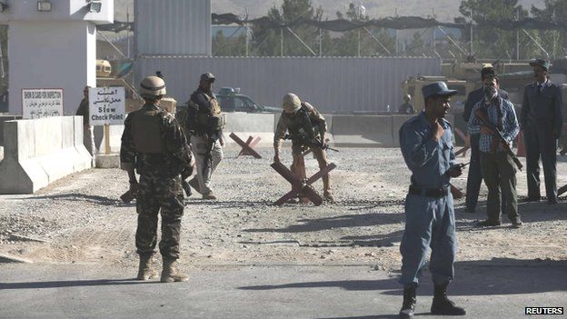 Afghan and foreign security personnel stand guard at the site of a blast (22 July 2014)