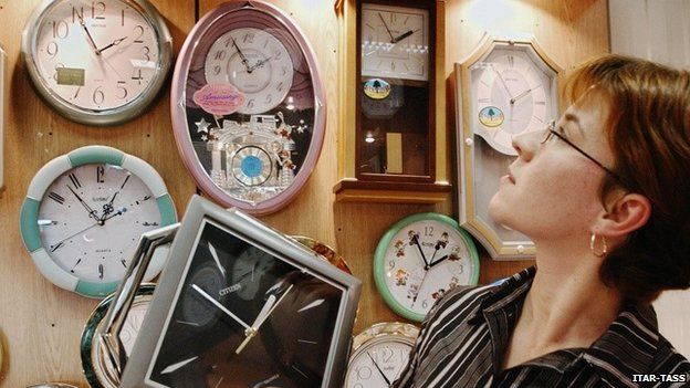 A woman looks at clocks of the Russian time zones