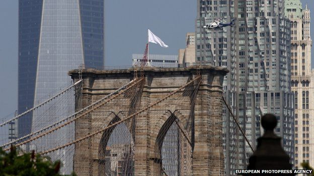 An NYPD helicopter flies over the Brooklyn Bridge inspecting white flags that were placed on the top of its two towers 22/07/2014