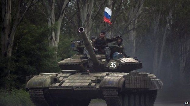 Pro-Russian rebels ride on a tank flying Russia's flag, on a road east of Donetsk, Monday