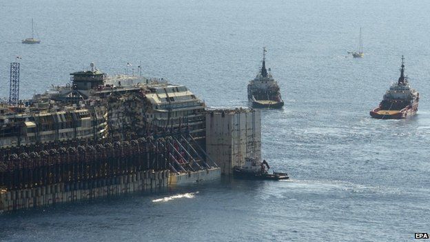 Two tugboats tow the Costa Concordia off the coast of Giglio Island