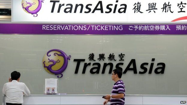 Local journalists wait in front of a TransAsia reservations desk at the Sungshan airport in Taipei, 23 July 2014