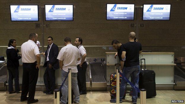 Passengers and airline staff stand near a check-in desk of an airline that cancelled its flight out of Tel Aviv at Ben Gurion International airport on 22 July 2014