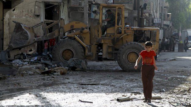 A boy walks along a damaged road as a front loader removes rubble at a site hit by what activists said was shelling by forces loyal to Syria"s President Bashar al-Assad in the al-Myassar neighbourhood of Aleppo July 14, 2014