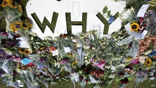 Flowers in tribute to the victims of flight MH17 are laid around a cutout reading "Why", near the entrance to the military airport in Eindhoven, southern Netherlands, 24 July 2014