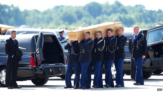 Dutch military personnel carry a coffin containing the remains of the victims of the MH17 plane crash to a waiting hearse at the airbase in Eindhoven on 24 July 2014.