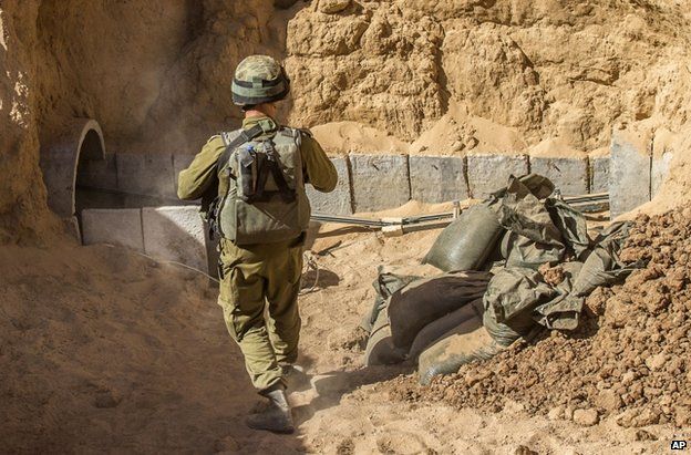 An Israeli officer walks by a tunnel on the Gaza-Israeli border which was allegedly dug by militants to launch attacks on Israel, 25 July