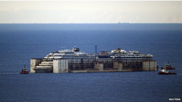 Tug boats tow the Costa Concordia cruise liner as they arrive outside a port near Genoa in northern Italy, where it will be being broken up for scrap, on 27 July 2014.