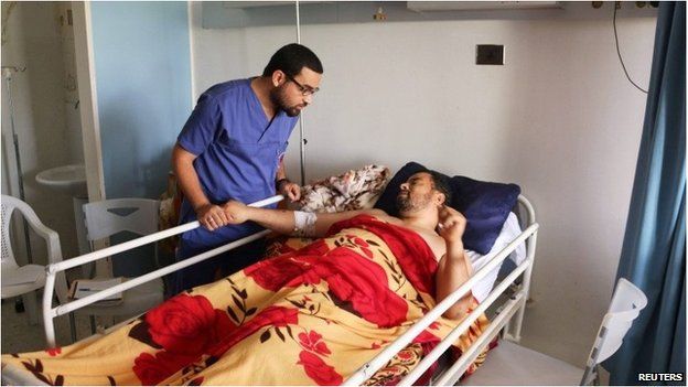 A man lies in a bed at Sbaah hospital, after he was injured in a shelling in Qaser Bin Ghashir, near the Tripoli International Airport on 26 July