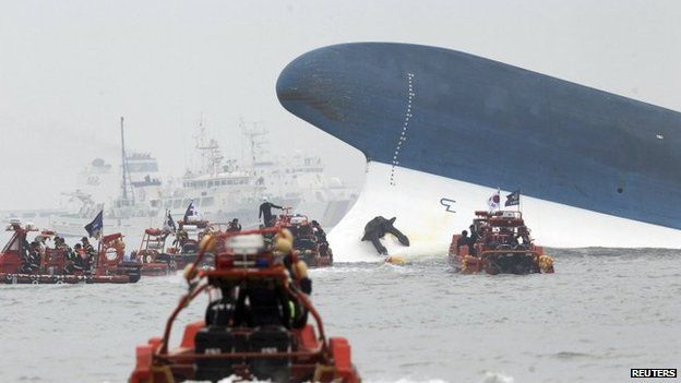 Part of the Sewol is seen as South Korean maritime policemen search for passengers in the sea off Jindo on 16 April 2014