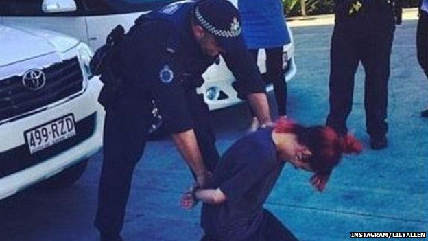 Police officer putting handcuffs on Lily Allen