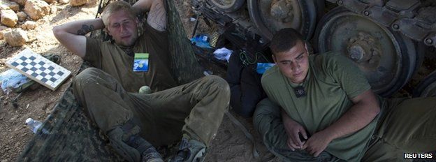 Israeli soldiers rest at a staging area outside the Gaza Strip, 27 July