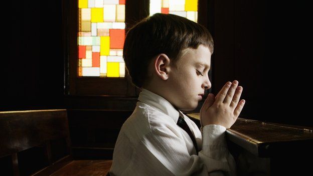 A boy prays in a church.