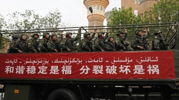 Paramilitary policemen stand on a truck as they travel past the Xinjiang International Grand Bazaar during an anti-terrorism oath-taking rally in Urumqi, Xinjiang on 23 May 2014.
