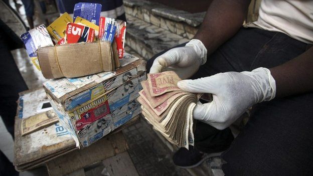 Liberian money exchanger wears protective gloves as a precaution to prevent infection with the deadly Ebola virus while transacting business with customers in downtown Monrovia, Liberia, 28 July 2014