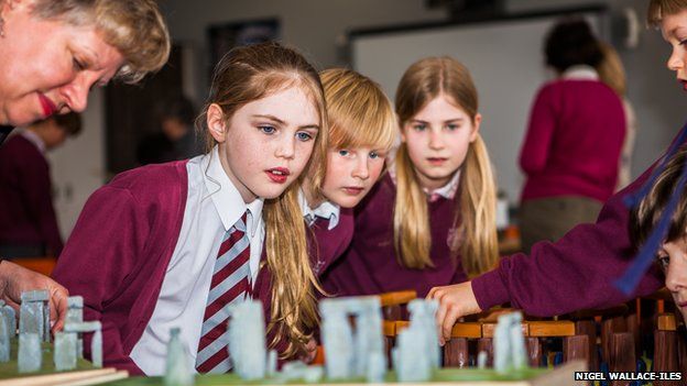 Children in a classroom look at a replica of Stonehenge