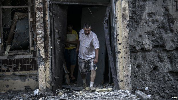 Man leaving bombed-out house in Donetsk, 29 Jul 14