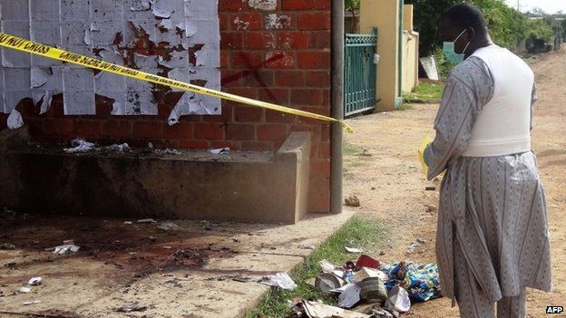 A police detective inspects the site of a suicide blast in the northern Nigerian city of Kano on 30 July 2014