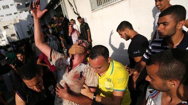 Palestinians react after the deaths at the market near Gaza City, 30 July