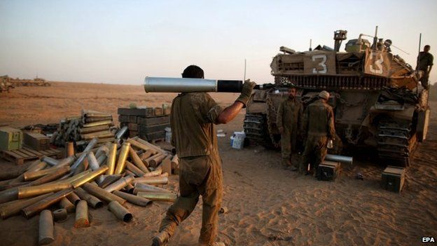 Israeli soldiers carries a shell next to a Merkava tank in a staging area, close to the Gaza Strip border, in southern Israel, 30 July 2014
