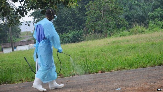 Aid worker spraying disinfectant outside a hospital in Liberia