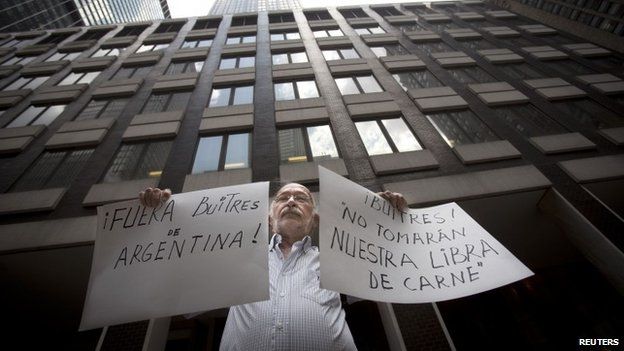 A protester holds up signs outside the office of a court-appointed mediator in New York on 30 July, 2014 reading