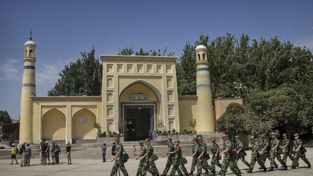 Chinese soldiers march in front of the Id Kah Mosque, China's largest, on 31 July 2014 in Kashgar, China