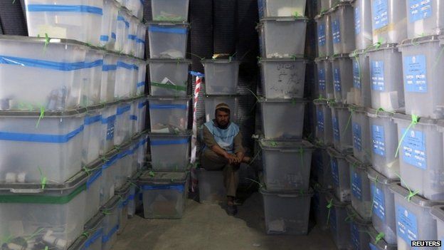 An Afghan election worker takes a break among ballot boxes to be counted for an audit of the presidential run-off in Kabul July 18, 2014.