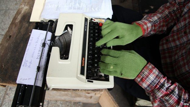 A Liberian typist at work using gloves as a protective measure to avoid the deadly Ebola virus in Monrovia (30 July 2014)