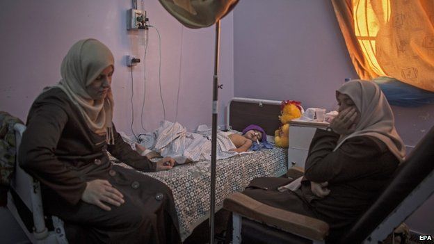 The mother and a friend of a child injured in an Israeli airstrike sit by her bed