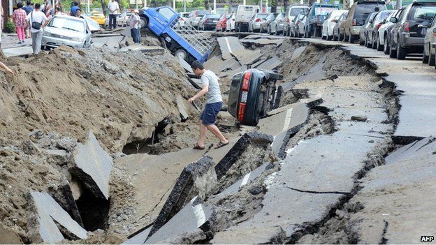 A resident crosses a damaged road in Kaohsiung on 1 August 2014