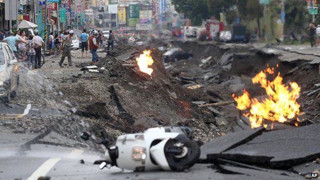 Vehicles are left lying on a destroyed street as part of the street is burning following multiple explosions from an underground gas leak in Kaohsiung, Taiwan, on 1 August 2014