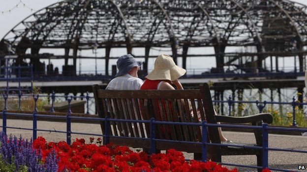 Couple on bench look at fire-damaged Eastbourne Pier