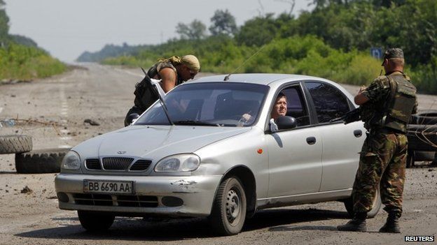 Ukrainian army servicemen check a car at a checkpoint outside the eastern Ukrainian village of Nikishyne (1 August 2014)