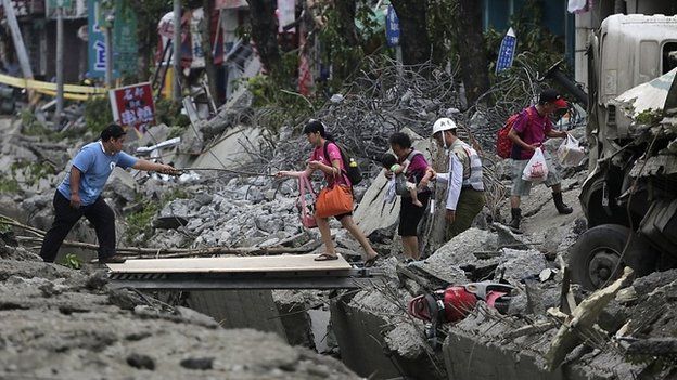 People walk across a gap caused by an explosion in Kaohsiung - 1 August 2014