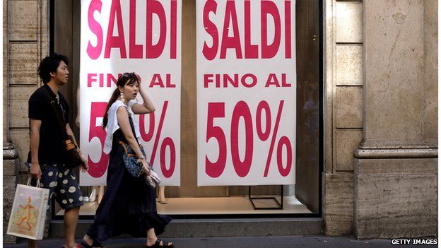 Shoppers outside shop with 50% Sale sign