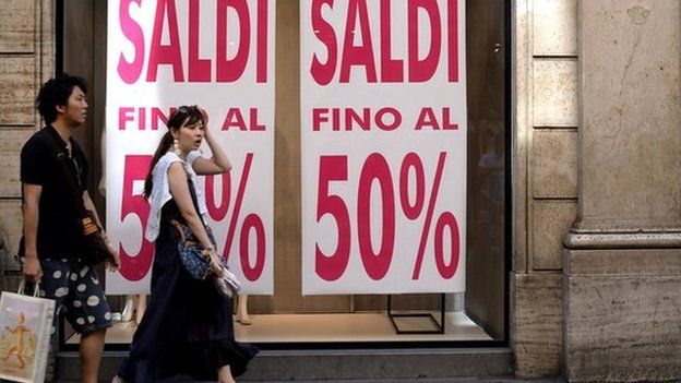Shoppers outside shop with 50% Sale sign