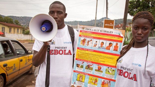 A couple taking part in a Ebola prevention campaign holds a placard with an Ebola prevention information message in the city of Freetown, Sierra Leone (6 August 2014)