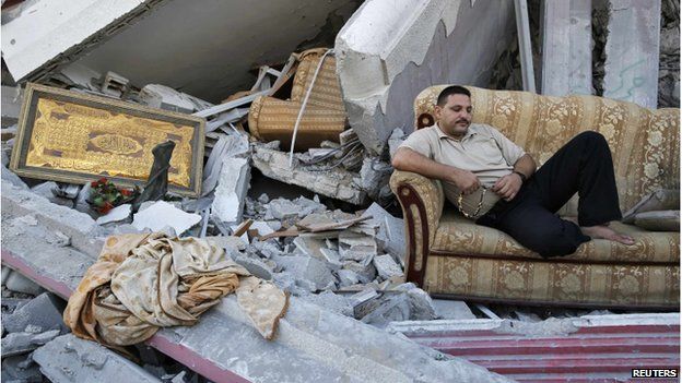 A man sitting on a sofa on top of a pile of rubble