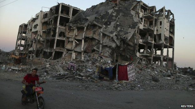 A Palestinian rides past residential buildings in Beit Lahiya town, which witnesses said was heavily hit by Israeli shelling and air strikes during the offensive in the northern Gaza Strip (7 August 2014)