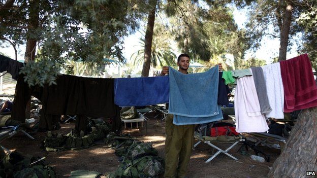 An Israeli reserve soldier hangs his laundry at an unspecified location near the Israeli border with the Gaza Strip (7 August 2014)