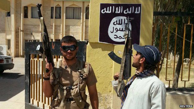 Islamic State militants stand guard after taking control of a government building in the Christian town of Bartella, Nineveh province - 7 August 2014