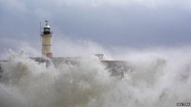 Waves crash against a lighthouse in Newhaven, East Sussex
