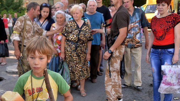 A young boy holds a loaf of bread as residents of the eastern Ukrainian city of Lysychansk queue to receive bread distributed as part of humanitarian aid (27 July 2014)