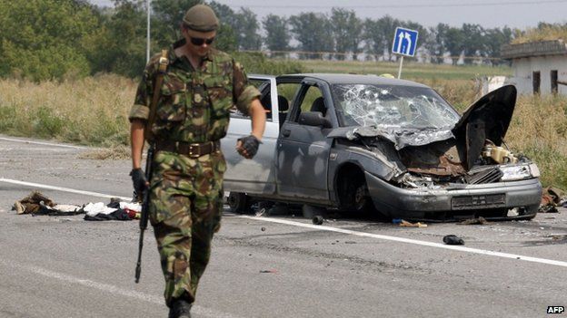 A Ukrainian soldier walks past a damaged car which was used by pro-Russian militants who tried to break through the checkpoint of Ukrainian forces, near the eastern Ukrainian city of Donetsk (11 August 2014)