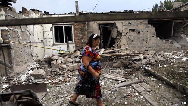 Woman walks past damaged house in Donetsk (11 August 2014)