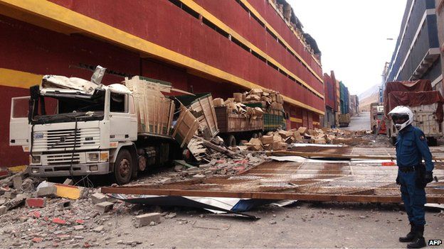 Picture of a lorries destroyed by parts of a building damaged by a quake and its aftershocks, in Iquique.