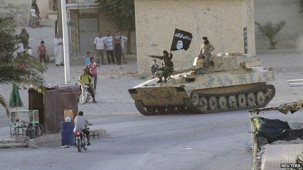 Residents watch Islamic State fighterson the streets of Syria's northern Raqqa province (30 June 2014)