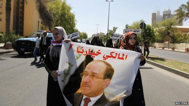 Iraqis carry portraits of incumbent Iraqi Prime Minister Nuri al-Maliki as they gather in support of him in Baghdad